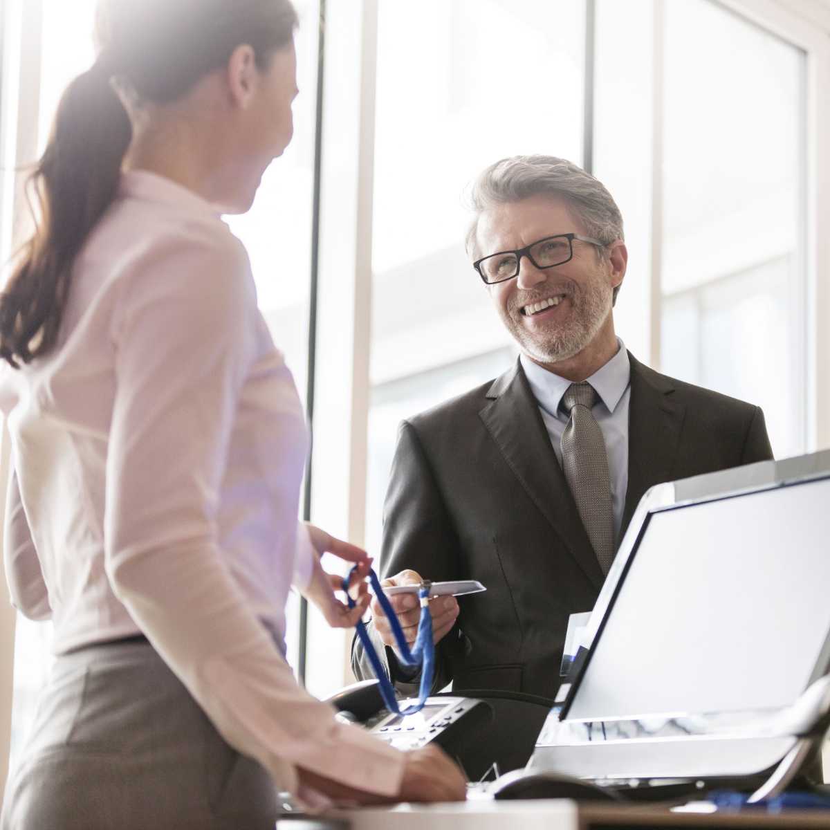 Receptionist overhandigd bezoeker een  bezoekerspas