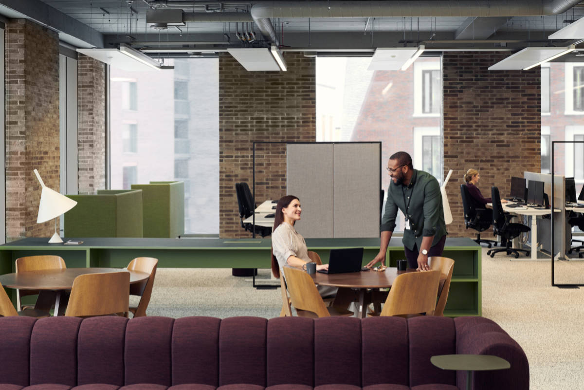 Male and female professional in an office environment sit down for a demo meeting